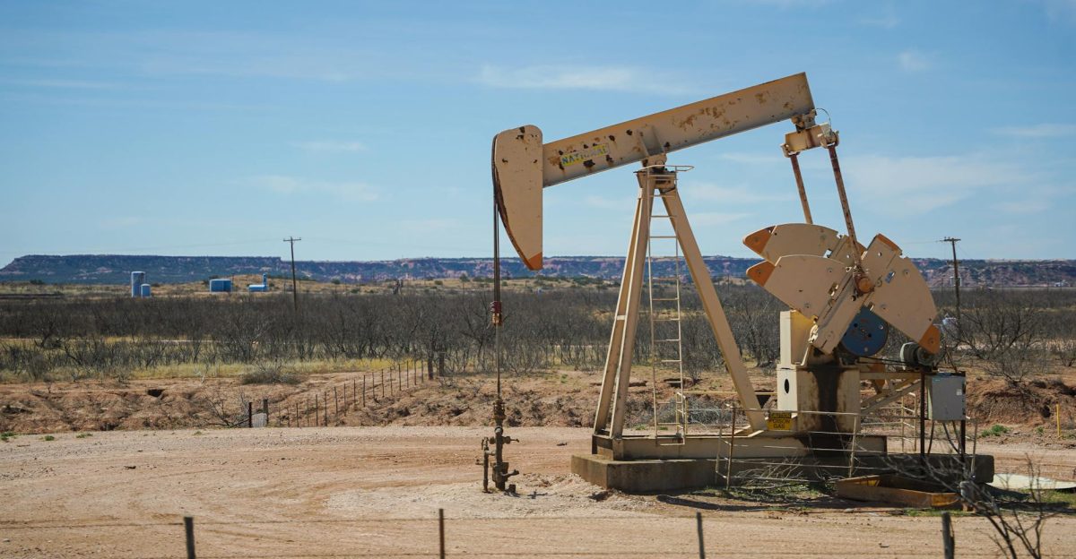 Industrial oil pumpjack in a desert setting under a clear blue sky illustrating oil extraction technology