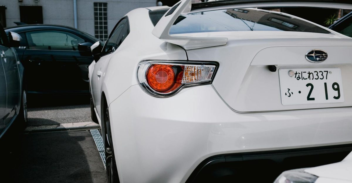 A stylish white Subaru BRZ parked in a city lot showcasing its sporty rear design