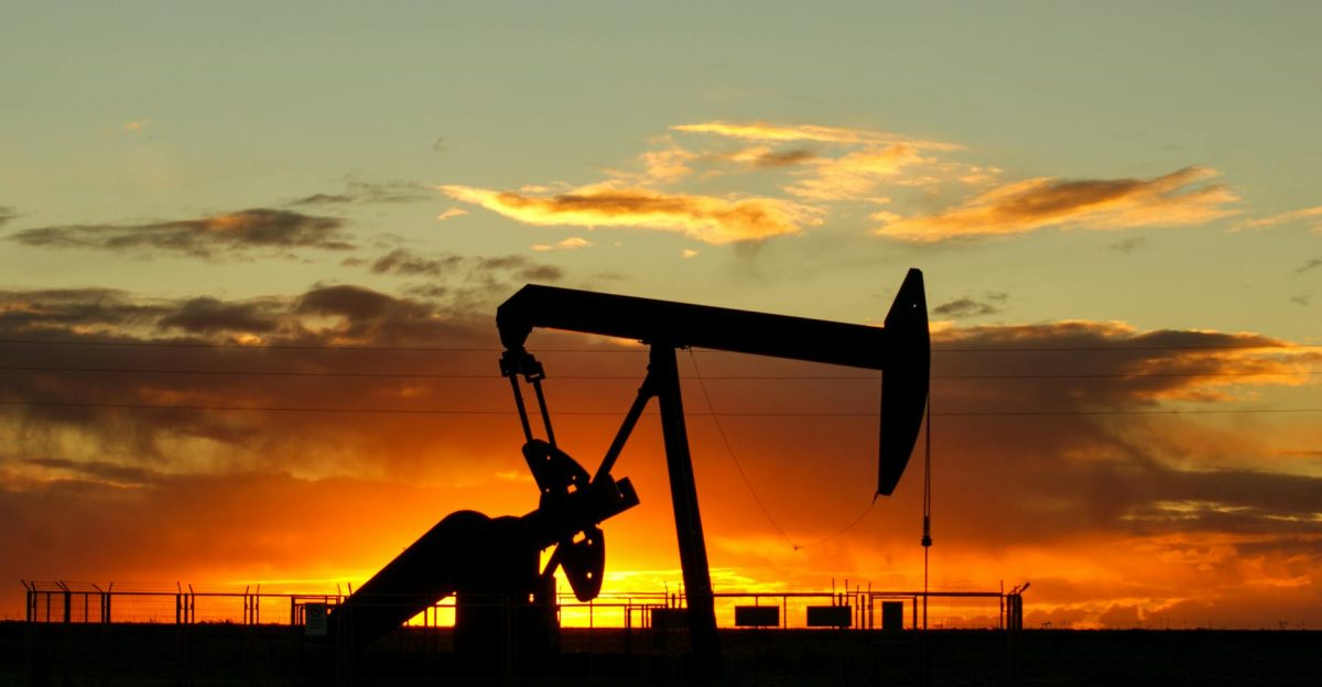 Dramatic silhouette of an oil pump jack against a vibrant sunset sky emphasizing energy extraction