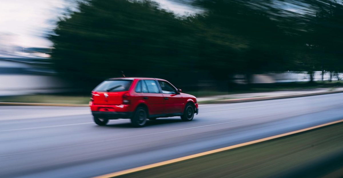 A red car speeding on a city road captured with motion blur showcasing dynamic motion