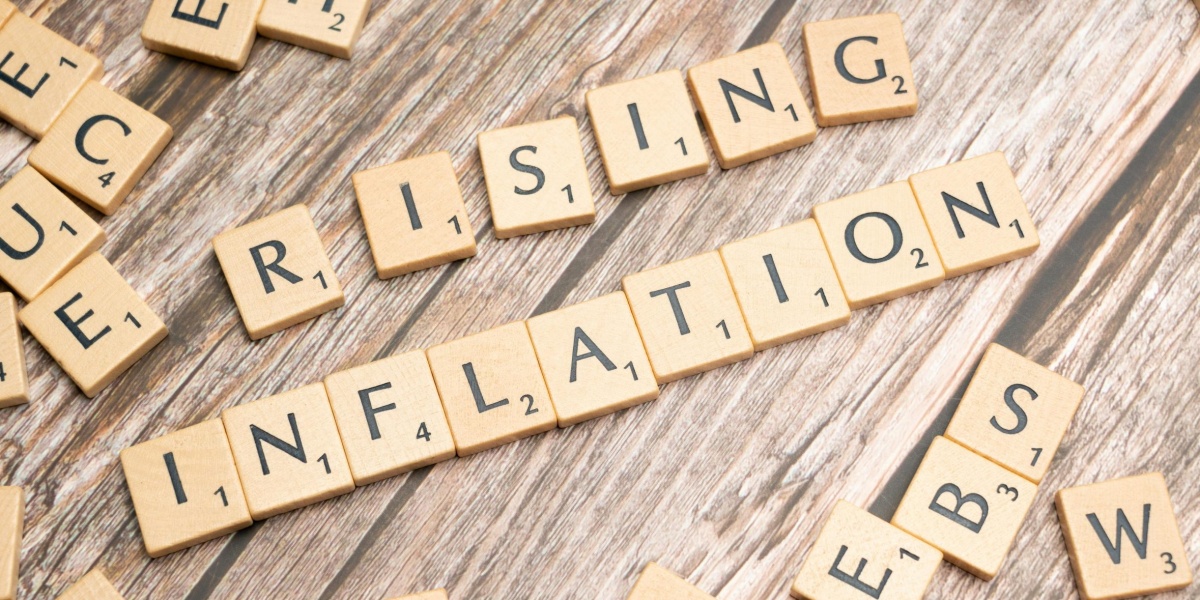 Wooden letter tiles spell 'rising inflation' symbolizing economic concerns.