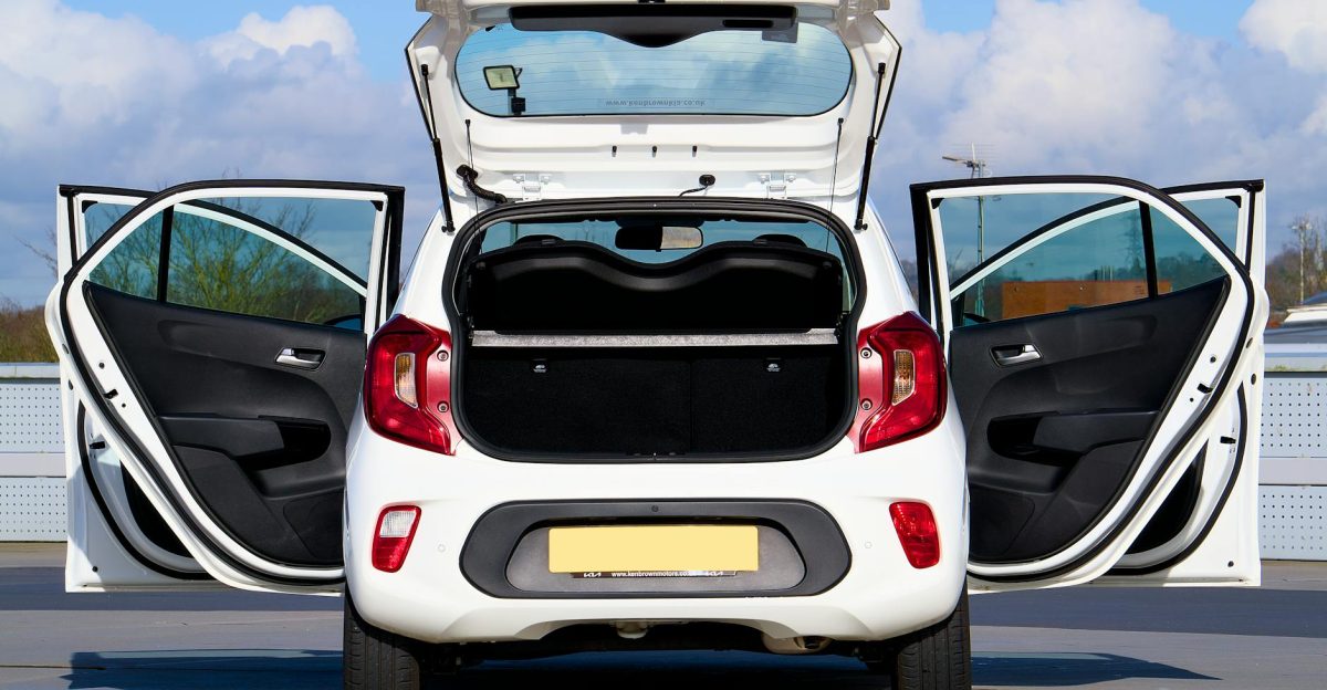 A white Kia Picanto displayed with all doors open from the rear view in Harlow England
