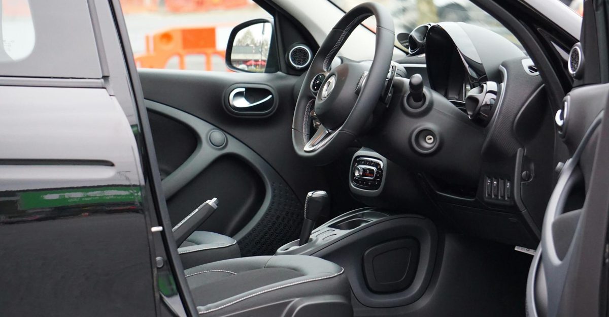 A sleek car interior showcasing the steering wheel and dashboard through an open door