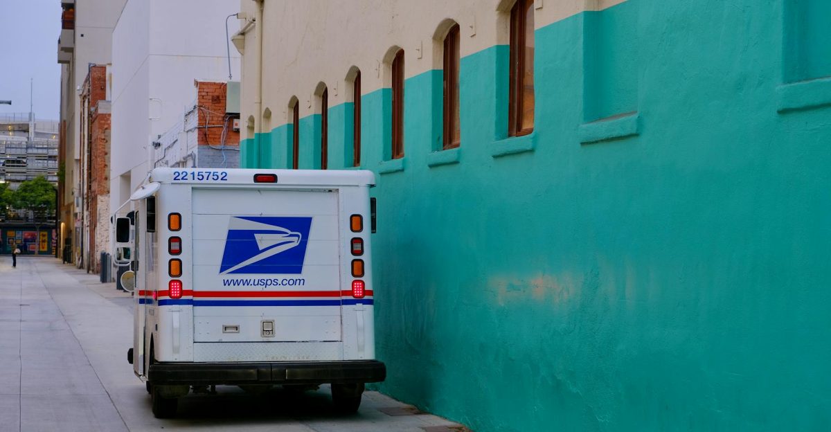 A USPS delivery truck parked in a vibrant urban alley beside colorful architecture