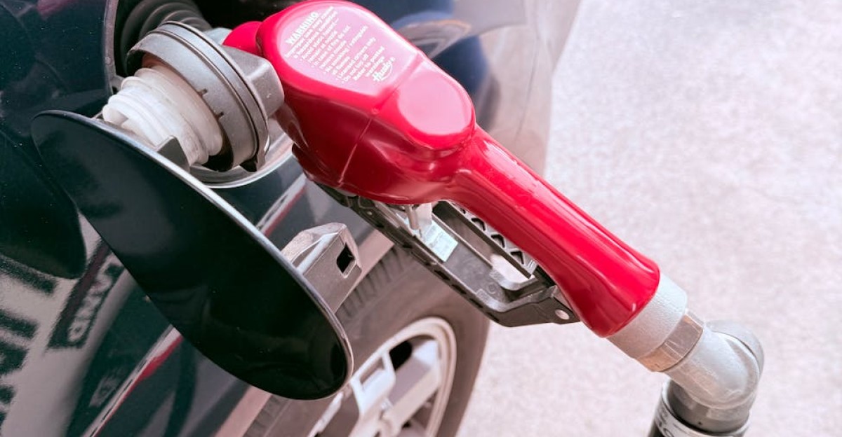 Close-up of a red gas pump fueling a car at a gas station depicting the refueling process