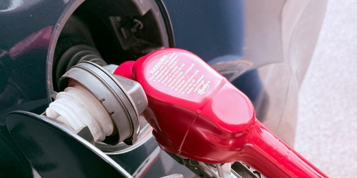 Close-up of a red gas pump fueling a car at a gas station, depicting the refueling process.