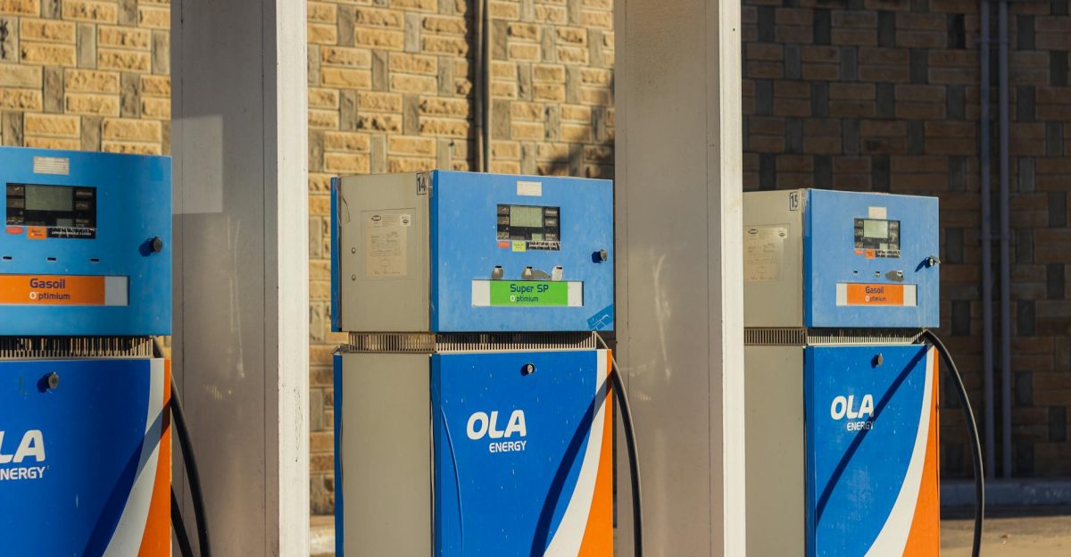 Three blue OLA Energy gas pumps at an outdoor station on a sunny day