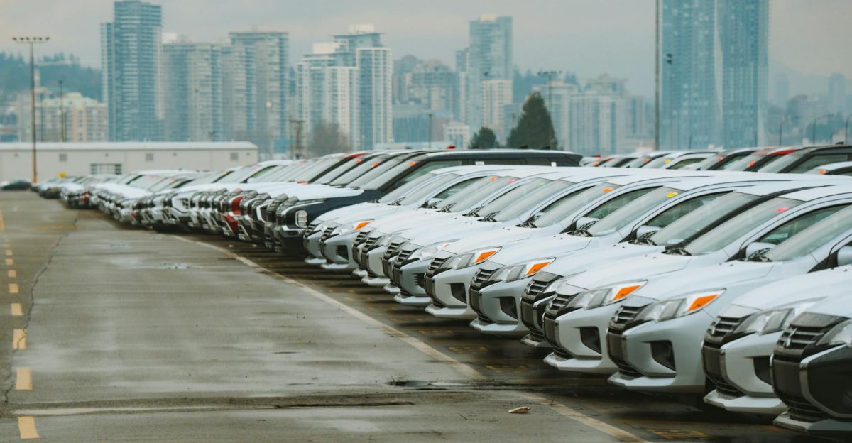White cars lined up in a parking lot with a city skyline backdrop