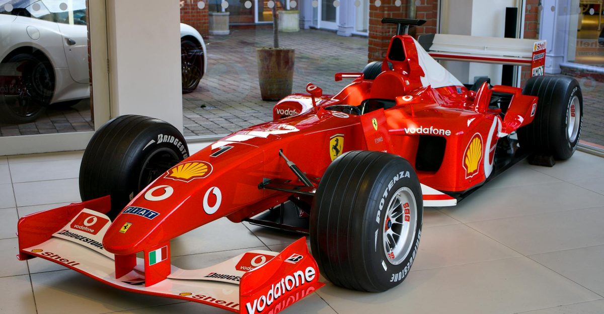 A striking red Formula 1 Ferrari race car displayed in a modern showroom setting