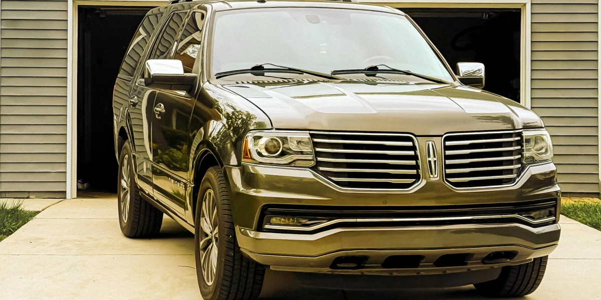 A sleek luxury SUV parked in front of a residential garage on a driveway.