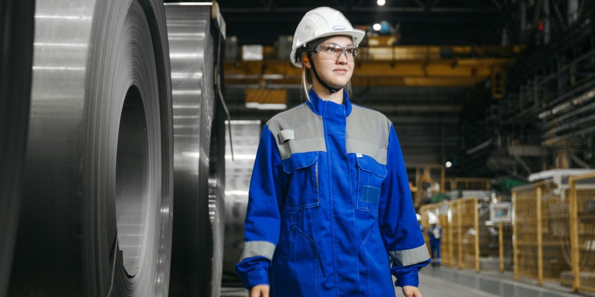Female industrial worker in protective gear at a steel manufacturing facility.