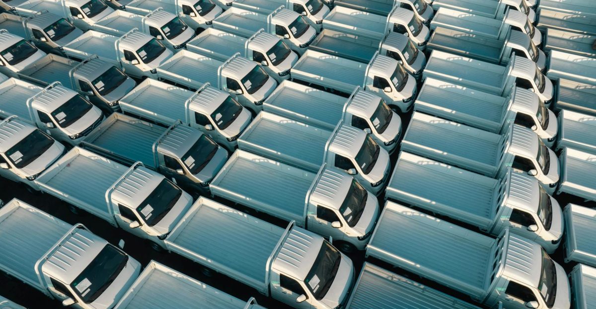 A top-down view of numerous white trucks parked in a grid pattern showing symmetry and industrial logistics