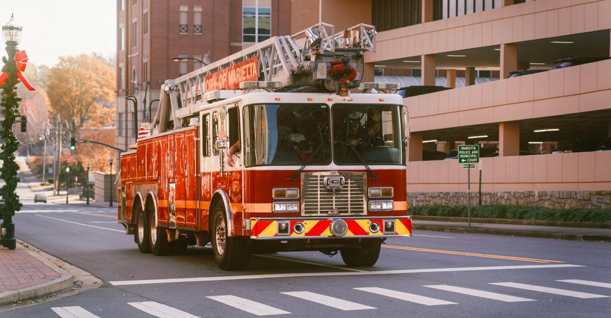 A red fire truck with a ladder drives down a city street in Marietta showcasing urban readiness