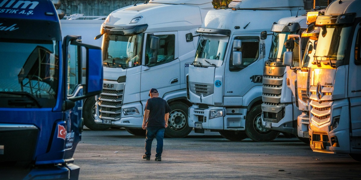 A man walks among parked trucks at sunset in an industrial area, creating a serene yet busy scene.