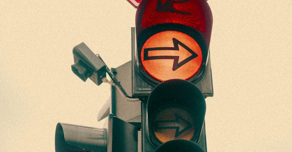 A vintage-style traffic light with a stop sign and yellow arrow urban setting