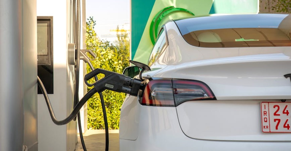 Tesla Model 3 electric vehicle charging at a station outdoors during the day