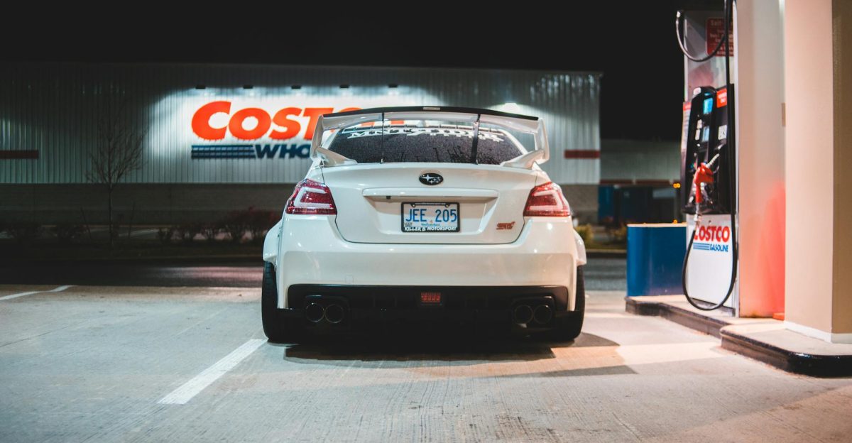 Contemporary white car parked near pump on fuel station at night in city