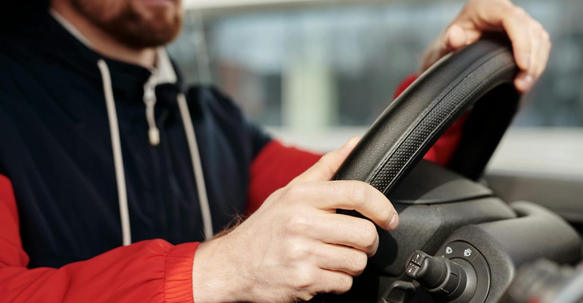 Focused man holding steering wheel driving in vehicle interior Close-up view with selective depth