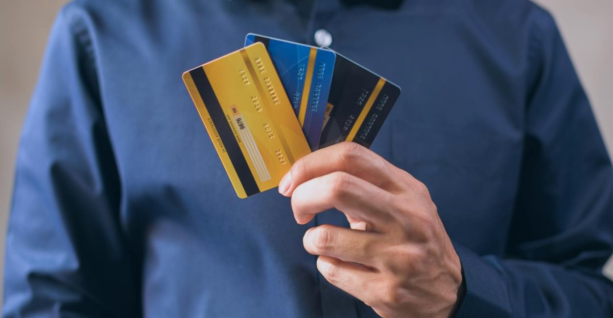Person holding three credit cards symbolizing finance security and e-commerce