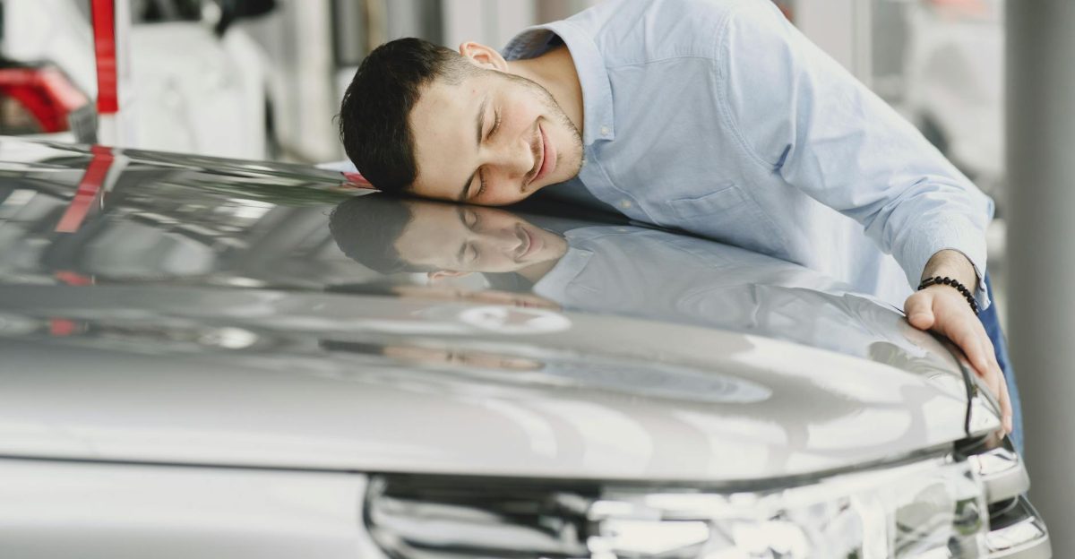 A man joyfully embracing a new car indoors reflecting happiness and satisfaction