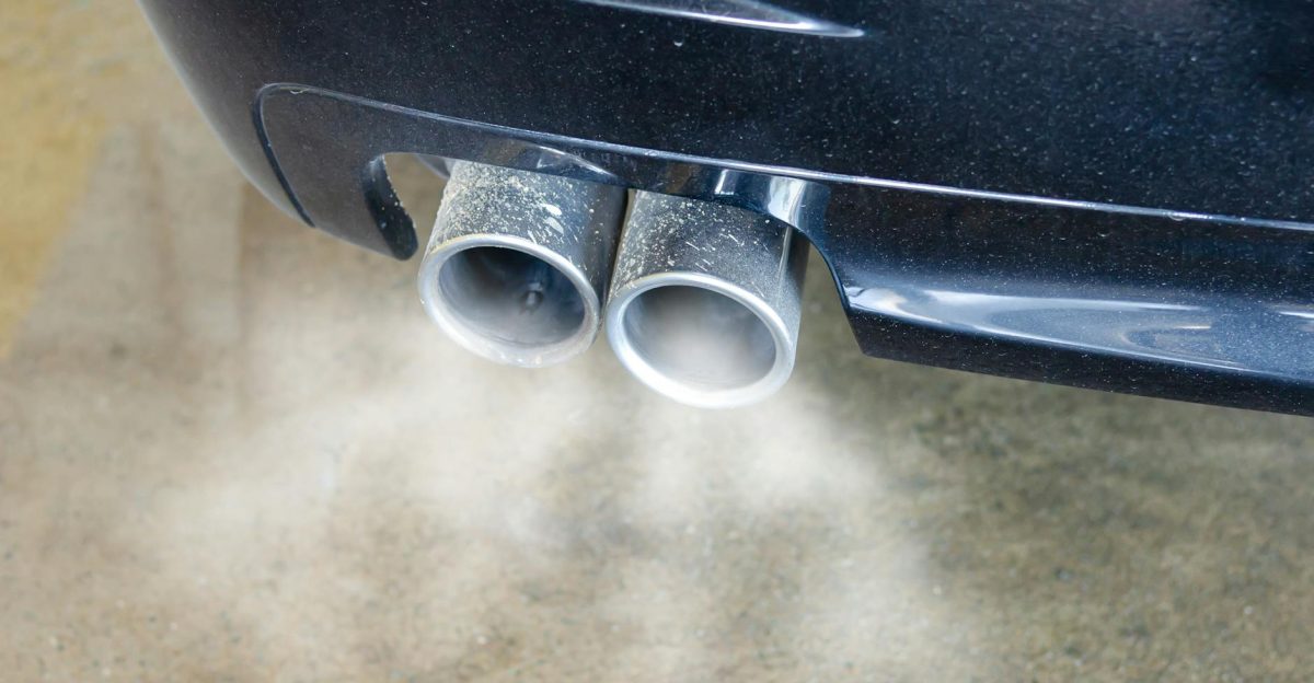 Close-up of a car s exhaust pipes emitting visible smoke highlighting air pollution