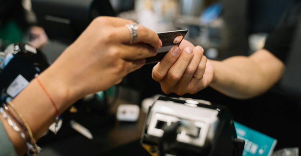 Close-up of hands completing a payment transaction at a retail checkout using a bank card