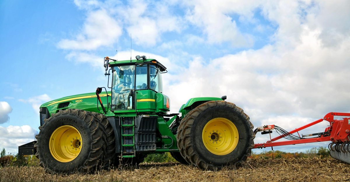 A vibrant green tractor plowing a field on a sunny day showcasing modern agriculture