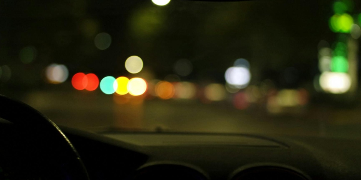 Blurred city lights seen from a car interior at night, depicting urban driving ambiance.