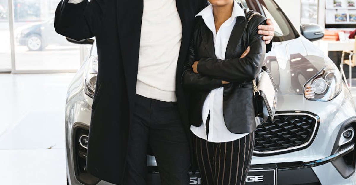 Interracial couple celebrating new car purchase at dealership showcasing car keys