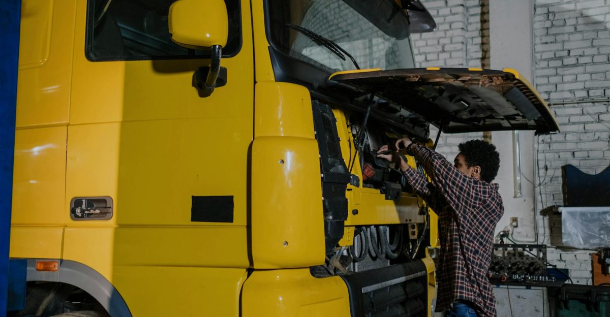 A mechanic working on a truck engine in an indoor mechanical workshop
