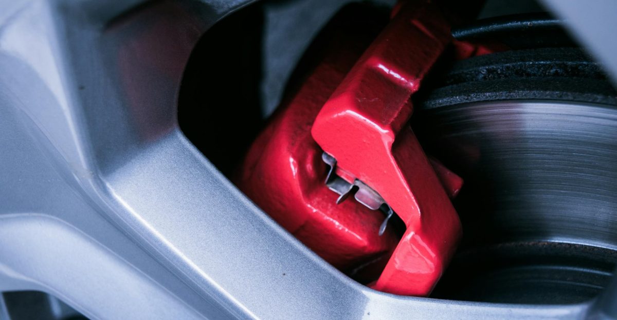Detailed photo of a red automotive brake caliper and disc brake in focus