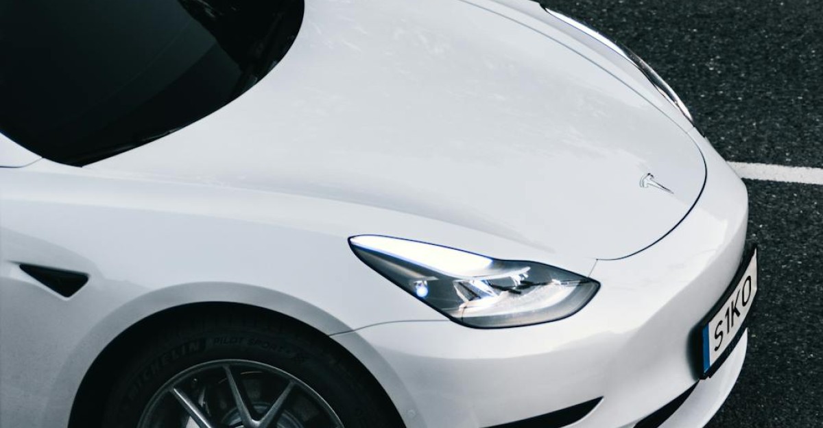 Top view of a sleek white Tesla electric car driving on a city street in Germany