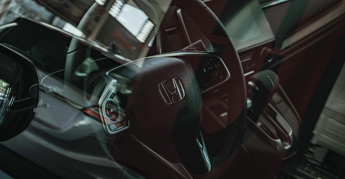Close-up of a Honda car interior highlighting the steering wheel through a reflective glass view