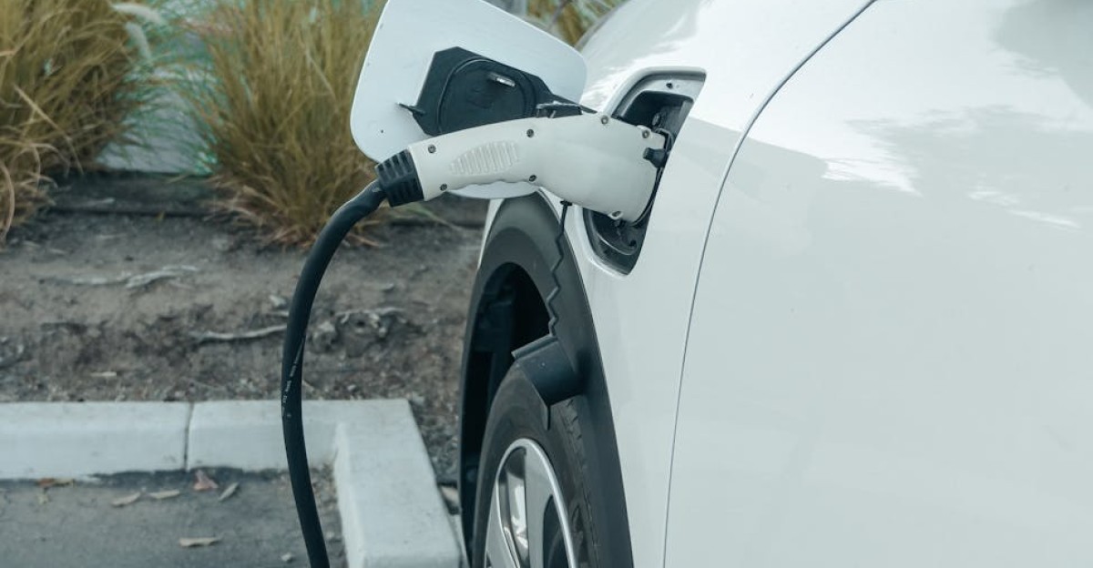 A white electric car plugged into a charger at an outdoor parking area promoting clean energy