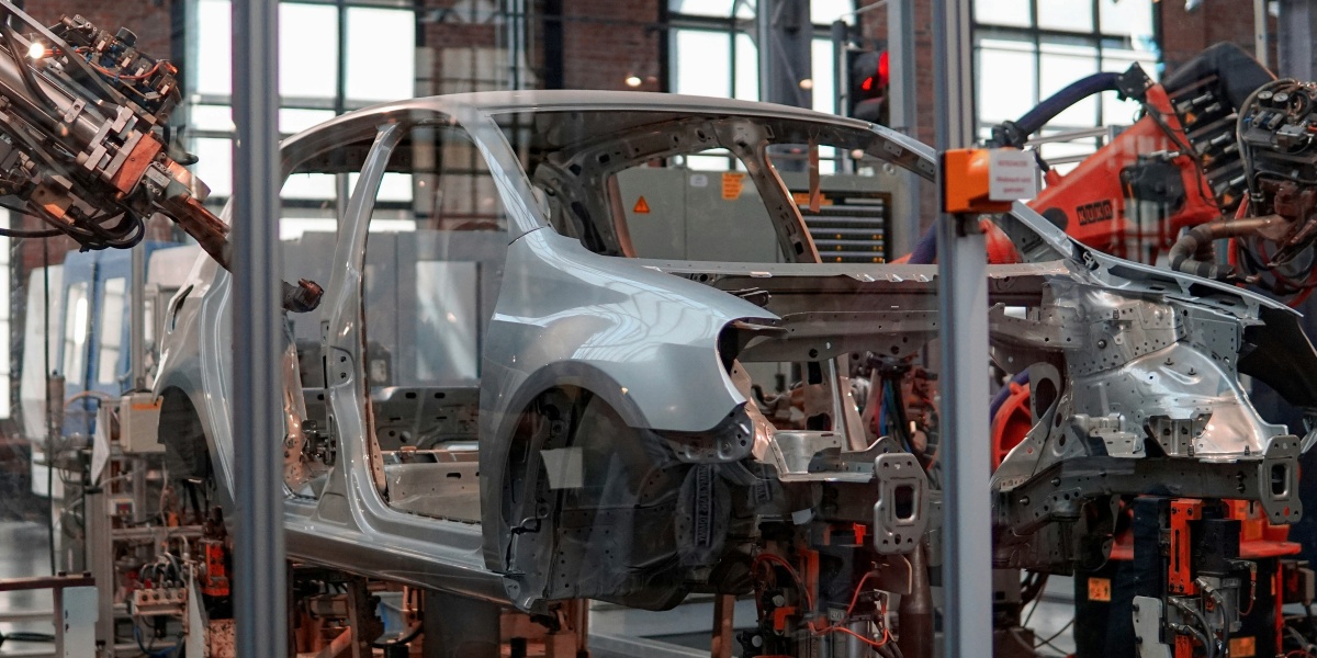 gray vehicle being fixed inside factory using robot machines