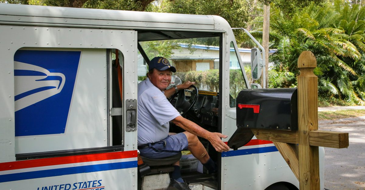man in blue dress shirt sitting on white and blue bus during daytime