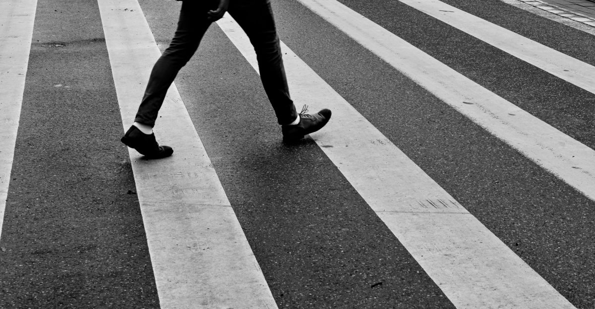 person in black pants and black sneakers walking on pedestrian lane