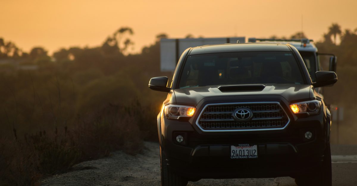 a black truck driving down a dirt road