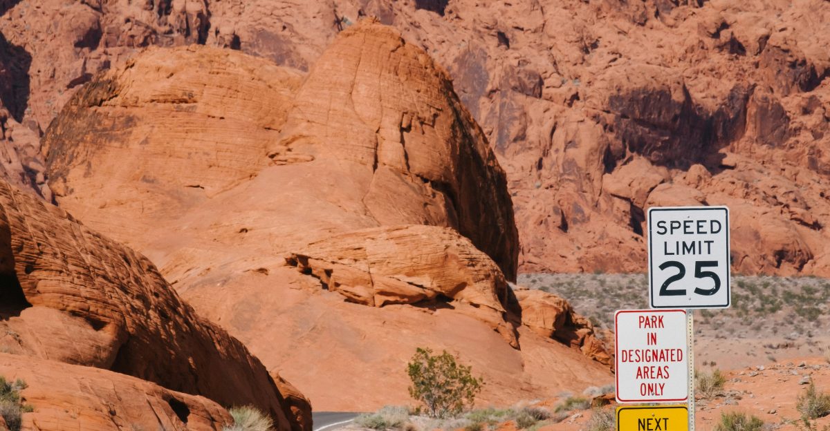 a road with a sign on it and a rocky mountain in the background