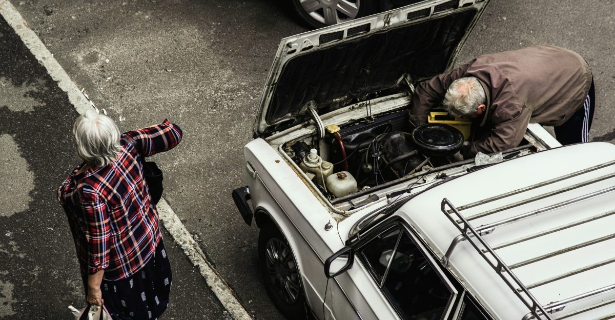 a man and a woman looking at a car with its hood open