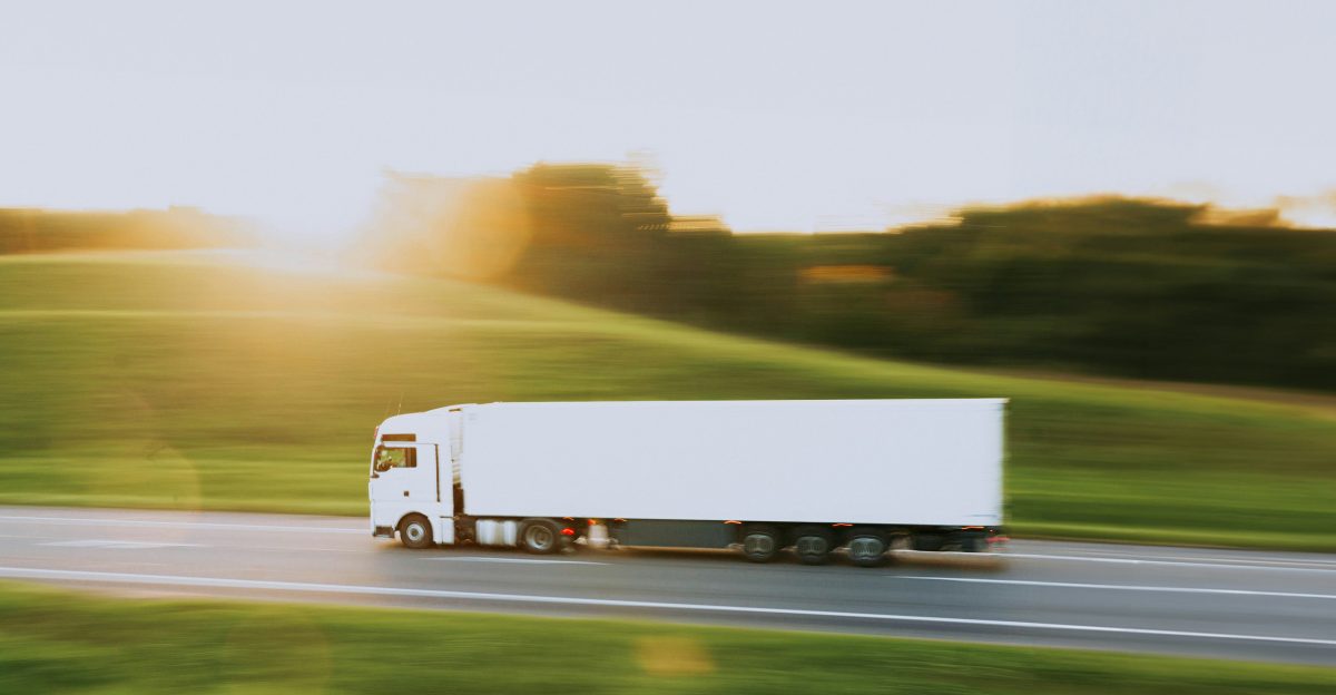 a white semi truck driving down a rural road