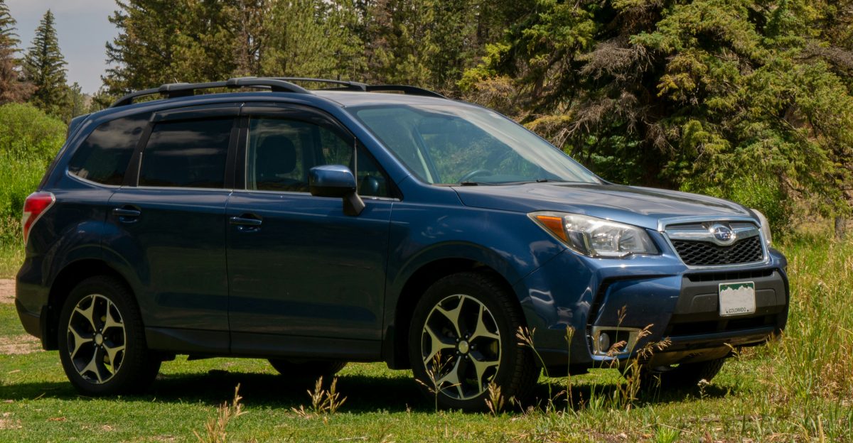 A blue subarunt parked in a grassy field