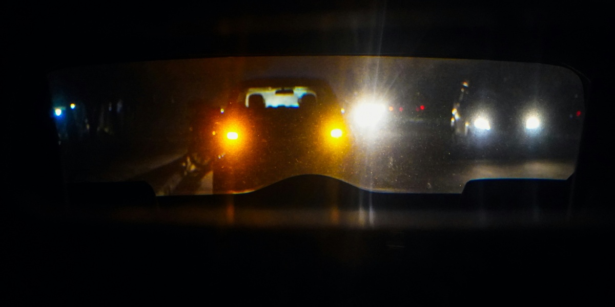 Cars driving at night reflected in a mirror.
